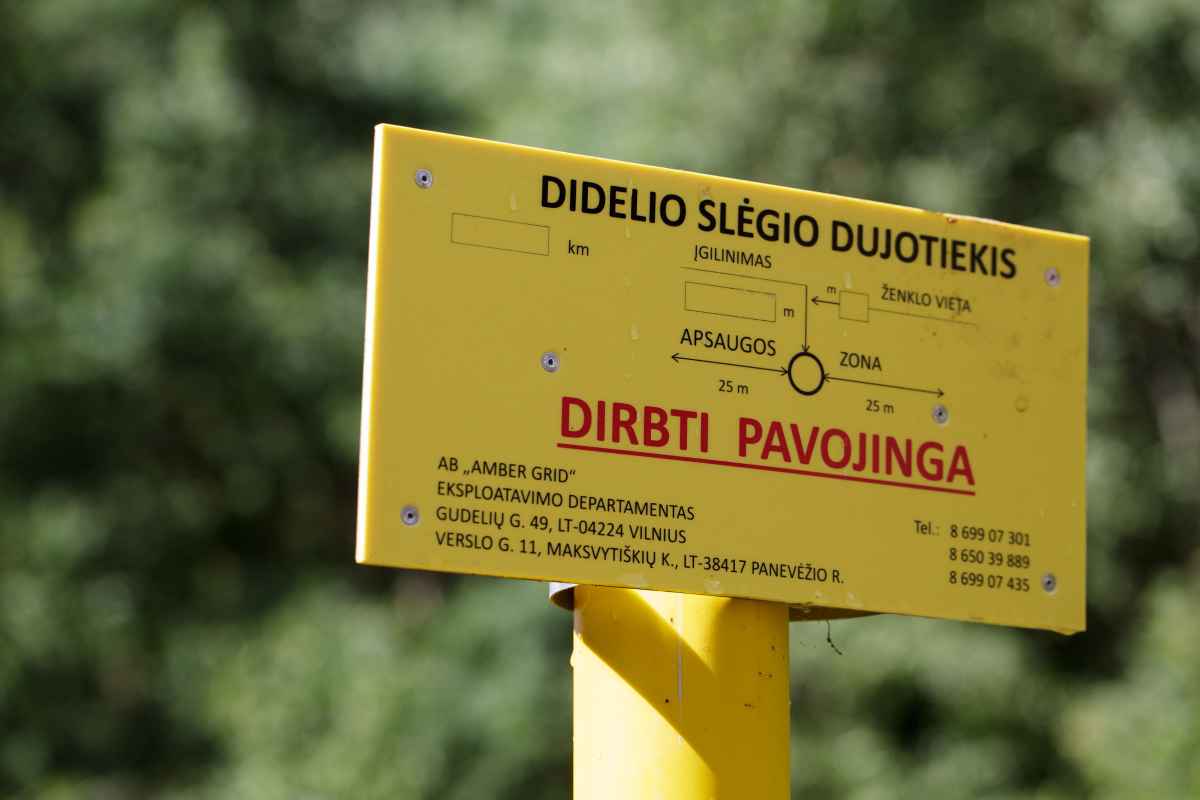 Geltonas ženklas su įspėjimu apie didelio slėgio dujotiekį su kontaktiniais duomenimis.